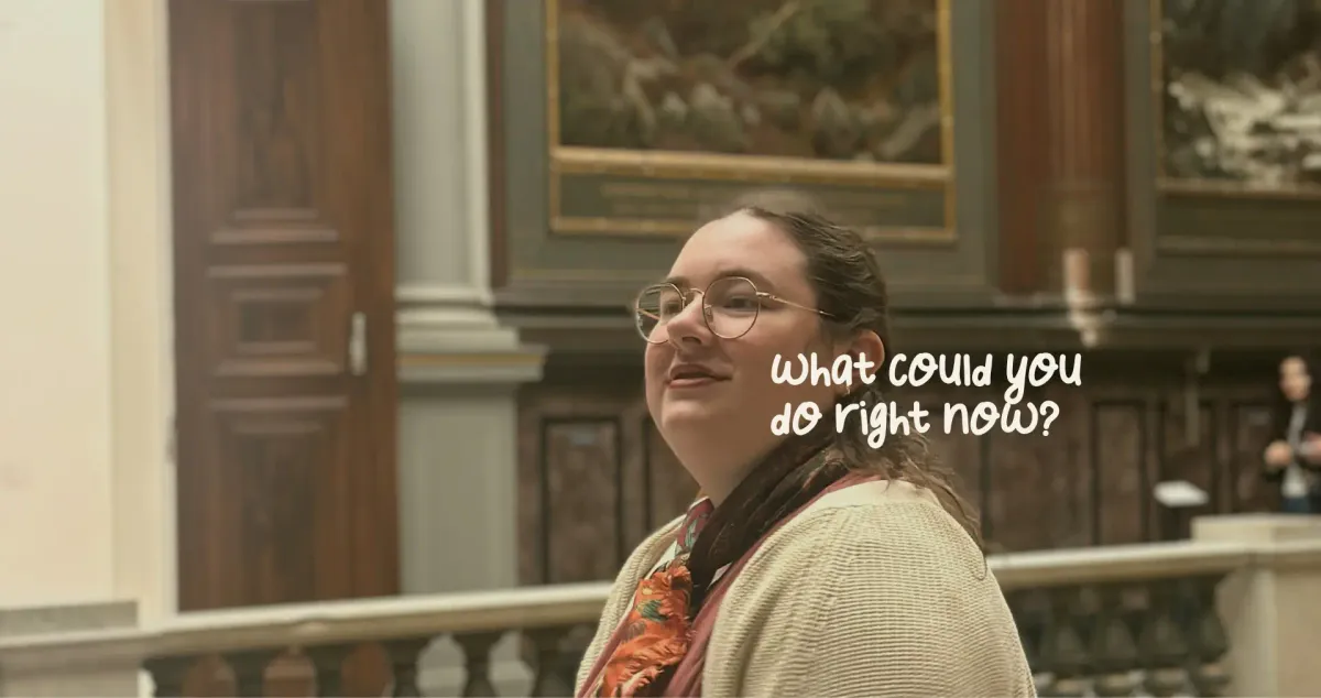 Mariia stands in a museum and looks off-camera.